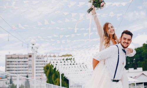 Elegant blonde in a white dress. Couple standing in a park. Bride with bouquet of flowers. Man in a white shirt