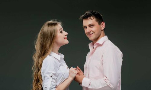 Portrait of a young couple standing against gray studio background