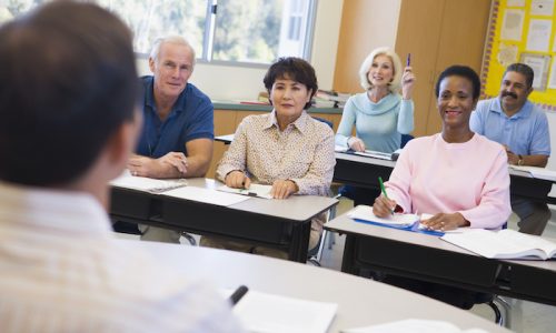Mature female student raising hand in class