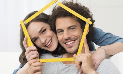 Happy Young Couple Making House Shape With Folding Ruler