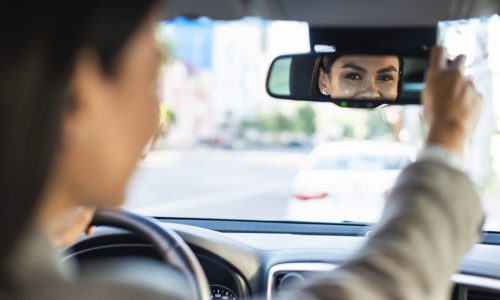 businesswoman-adjusting-her-rear-view-car-mirror